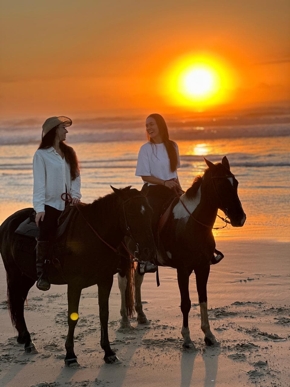 Bruna e Bianca, fundadoras das Desamigadas, a cavalo no pôr do sol na praia